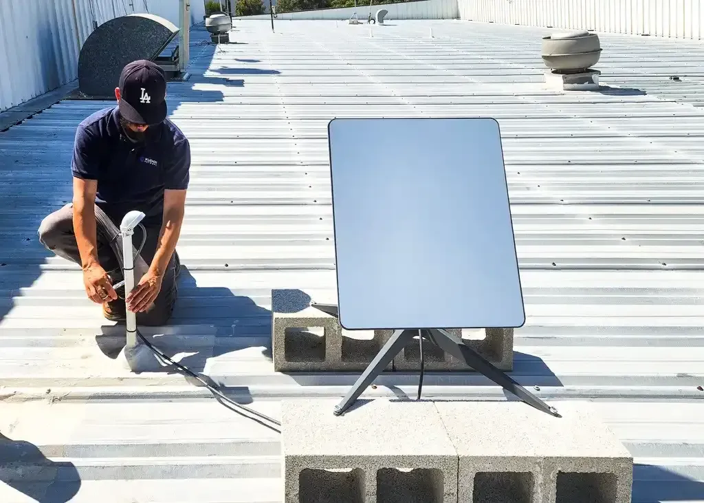 Installer setting up a Starlink dish on a commercial metal rooftop